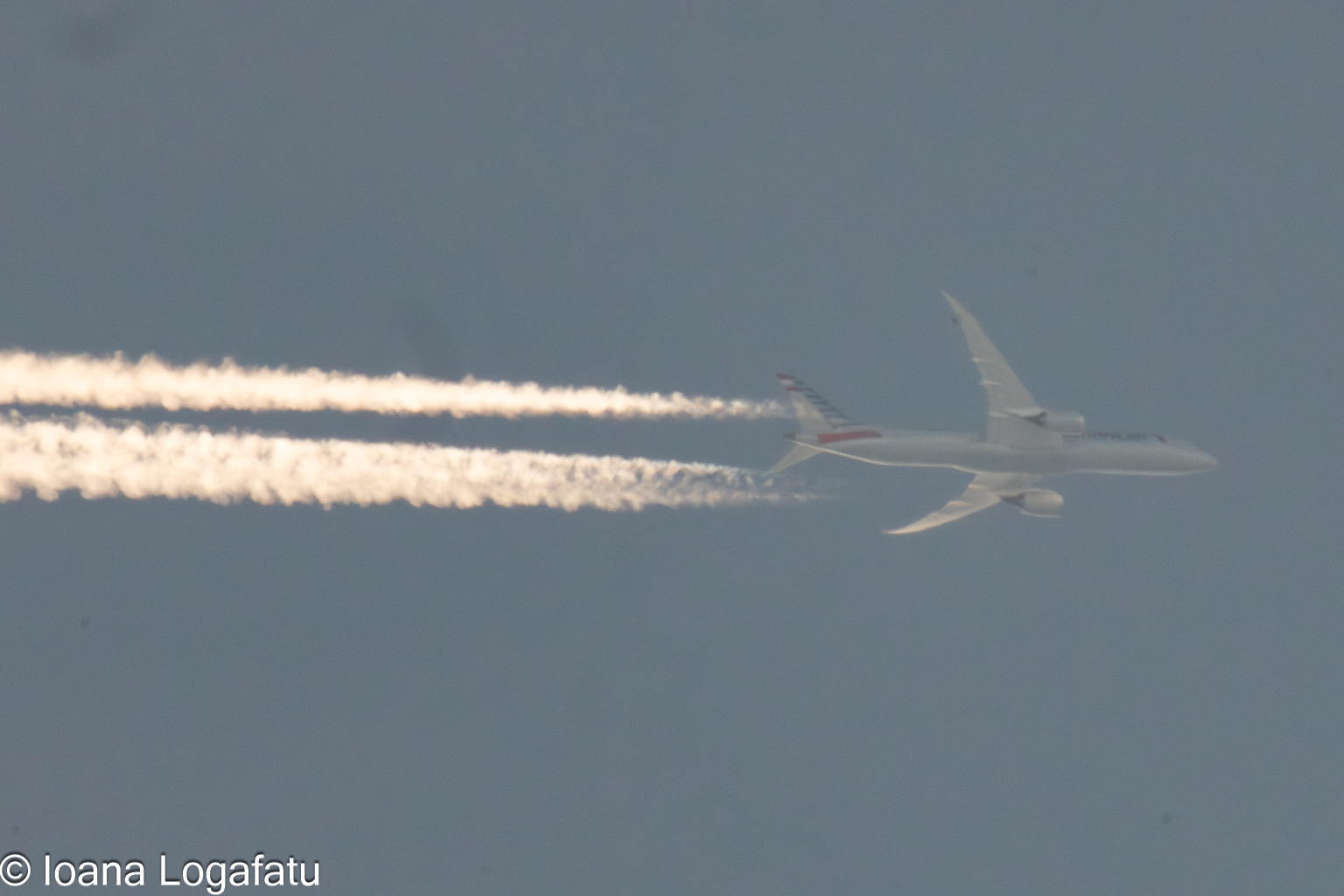 Clouds dance with a soaring airplane trail